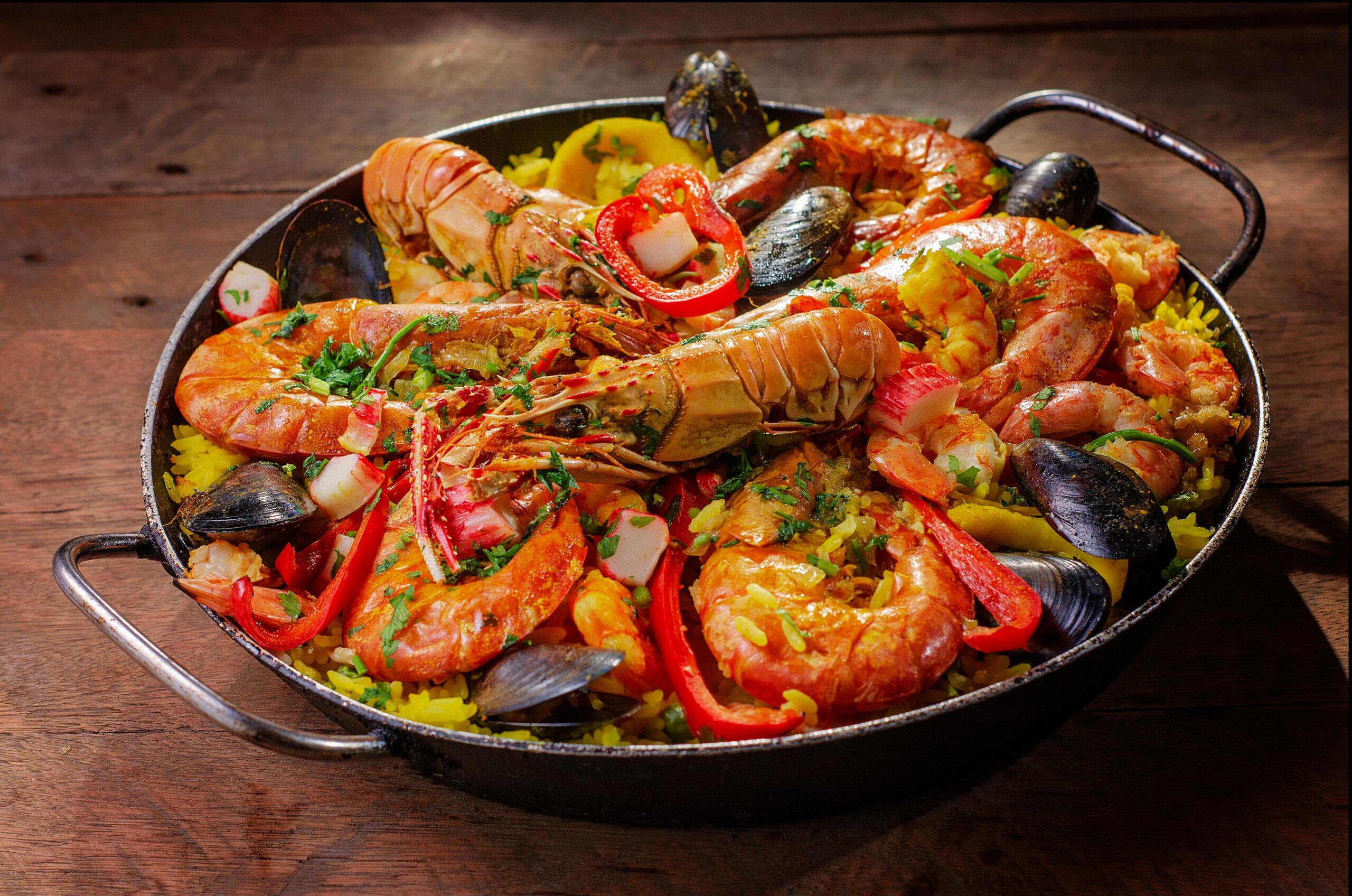 A vibrant and flavorful seafood paella served in a pan with mussels and shrimp.